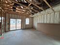 Spacious unfinished living room with exposed beams, insulation, sliding glass doors, and natural light at 47734 W Kenner Dr, Maricopa, AZ 85139