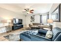 Living room with hard wood floors, ceiling fan, gray sofa, blue easy chair and ottoman, television and art on the wall at 4950 N Miller Rd # 231, Scottsdale, AZ 85251