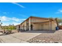 A charming single-story home boasts a covered carport, desert landscaping, and a long, paved driveway under a clear sky at 635 W Pecos Ave, Mesa, AZ 85210