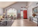 Bright and airy living room with vaulted ceilings, wood floors, and a red front door at 9116 W Acoma Dr, Peoria, AZ 85381