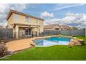 Backyard showcasing a sparkling pool with rock features, artificial turf, and a covered patio at 11234 W Roma Ave, Phoenix, AZ 85037