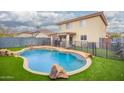 Home with a sparkling backyard pool, mature palm tree, and artificial turf at 11234 W Roma Ave, Phoenix, AZ 85037
