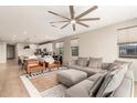 Open concept living room with modern fan, neutral colors, and lots of natural light at 17845 W Red Fox Rd, Surprise, AZ 85387