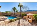 Backyard pool with water feature, lush landscaping, palm trees, an outdoor fireplace, and desert scenery at 2325 W Mineral Rd, Phoenix, AZ 85041
