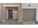 Close up of townhome exterior with brick accents, garage door, and small window by entrance at 2825 W Eagle Talon Rd, Phoenix, AZ 85085
