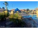 Community pool with rock waterfall feature, lounge chairs, and palm trees at 1306 N Lantana N Pl, Casa Grande, AZ 85122