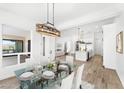 Open-concept dining room featuring a glass-top table, stylish chandelier, and views into the modern kitchen and living area at 13930 E Barwick Dr, Scottsdale, AZ 85262