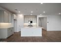 Bright, open kitchen with white cabinets, a large island, stainless steel appliances and hard wood floors at 17307 W Via Dona Rd, Surprise, AZ 85387