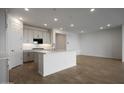 Modern kitchen showcasing an island with pendant lighting and an open layout with hardwood-style floors at 17307 W Via Dona Rd, Surprise, AZ 85387