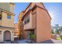 View of a two-story townhome with brown stucco and some small plants in front of the entry at 1940 N 78Th Gln, Phoenix, AZ 85035