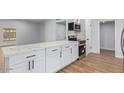 Stylish kitchen with white cabinetry, stainless steel appliances, quartz countertops, and wood floors at 10839 W Peoria Ave, Sun City, AZ 85351