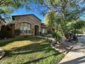 A charming stone-clad home with lush green lawn, mature trees and desert landscaping at 1131 W Sierra Madre Ave, Gilbert, AZ 85233