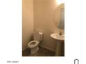 A simple half-bathroom featuring a white toilet and a pedestal sink with a round mirror at 1709 W Pollack St, Phoenix, AZ 85041