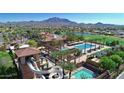 Aerial view of community amenities including pools, water slide, clubhouse, and lake with mountain views at 6271 S Twilight Ct, Gilbert, AZ 85298