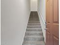 Carpeted staircase with a white handrail, leading upwards next to a solid wood door at 14250 W Wigwam Blvd # 1022, Litchfield Park, AZ 85340