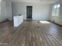 Spacious room featuring wood-look tile flooring, white walls, a window, and multiple doorways leading to other rooms at 17296 W Desert Sage Dr, Goodyear, AZ 85338