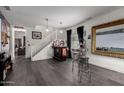 Open living room with bar setup, staircase, and dark vinyl plank flooring at 18316 N Soft Wind Dr, Maricopa, AZ 85138