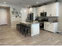 Well-lit kitchen features a granite island with seating, stainless steel appliances, and white cabinets at 19864 W San Juan Ave, Litchfield Park, AZ 85340