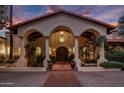 Grand home exterior with a tiled roof, arched entryway and well-manicured landscaping, lit by elegant outdoor lighting at 5254 E Arroyo Rd, Paradise Valley, AZ 85253