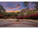 Exterior shot of a stone fountain with flowering desert plants and colorful sunset skies in the background at 5254 E Arroyo Rd, Paradise Valley, AZ 85253