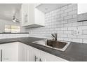 Close-up of the kitchen sink, white cabinets, subway tile backsplash, and stainless steel faucet at 749 E Montebello Ave # 228, Phoenix, AZ 85014