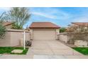 Beige two car garage and private driveway with a red-tiled roof surrounded by desert landscaping at 10957 E Hope Dr, Scottsdale, AZ 85259