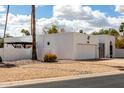 Charming single-story home boasts a pristine white exterior, low maintenance landscaping, and mature desert palms at 115 E Piping Rock Rd, Phoenix, AZ 85022