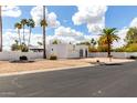 Charming single-story home boasts a pristine white exterior, low maintenance landscaping, and mature desert palms at 115 E Piping Rock Rd, Phoenix, AZ 85022