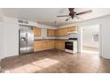 Spacious kitchen with wood cabinets, tile floors, and stainless steel refrigerator provides a functional cooking space at 1427 W 6Th Dr, Mesa, AZ 85202