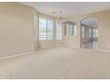 Bright and airy living room showcasing neutral carpeting, large windows, and an archway leading to other spaces at 4116 W Milada Dr, Laveen, AZ 85339