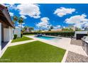 Landscaped backyard features a rectangular pool and lush green lawn with palm trees under a blue sky at 9675 E Cinnabar Ave, Scottsdale, AZ 85258