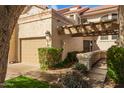 Home exterior featuring a garage, desert landscaping, and a covered entry with a pergola at 9705 E Mountain View Rd # 1056, Scottsdale, AZ 85258