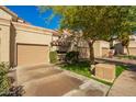 Exterior view featuring a two-car garage, lush green lawn and mature desert landscaping at 9705 E Mountain View Rd # 1056, Scottsdale, AZ 85258