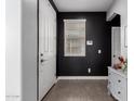 Modern entryway showcasing black accent wall, white door, laminate floors, and stylish white dresser at 14175 W Bronco Trl, Surprise, AZ 85387