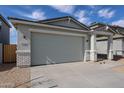 Well-maintained home with a grey garage door, concrete driveway, and desert landscaping at 17266 W Daley Ln, Surprise, AZ 85387