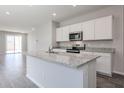 Modern kitchen featuring a large island with granite countertops, white cabinets, and stainless steel appliances at 18227 W Daley Ln, Surprise, AZ 85387