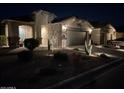 Charming single-story home featuring a two-car garage, desert landscaping, and inviting exterior lighting at night at 30444 N Bismark St, San Tan Valley, AZ 85143