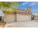 Beige two-story home with a red tile roof and spacious three-car garage on concrete driveway at 4831 N 93Rd Dr, Phoenix, AZ 85037
