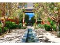 Building entrance with water feature, lush landscaping, and flowers at 6166 N Scottsdale Rd # C4004, Paradise Valley, AZ 85253