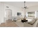 Bright living room with modern furnishings, fan, light wood floors, and natural light from a large window at 7056 W Caron Dr, Peoria, AZ 85345