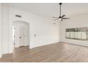 Spacious living room features light wood floors, a ceiling fan, and large window at 7056 W Caron Dr, Peoria, AZ 85345