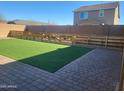 The backyard has a paver patio, artificial turf, and a partially constructed wooden fence at 9207 W Sells Dr, Phoenix, AZ 85037