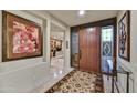 Elegant foyer features a custom wood door, intricate tile flooring, and artful decor leading to an office at 10567 E Fernwood Ln, Scottsdale, AZ 85262