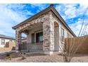 A cozy, covered porch showcasing stone columns and decorative railing, perfect for outdoor relaxation at 16517 S 7Th Pl, Phoenix, AZ 85048