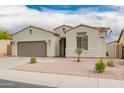 Close up of single-story home with neutral paint, well-manicured front yard and two car garage at 1827 S 237Th Dr, Buckeye, AZ 85326