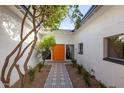 Inviting front entrance with decorative tiling, a vibrant orange front door, and mature landscaping at 2632 E Mountain View Rd, Phoenix, AZ 85028