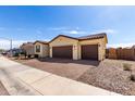 Single-story home with a three-car garage, brick driveway, and desert landscaping at 40385 W Haley Dr, Maricopa, AZ 85138