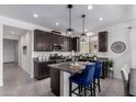 Modern kitchen with dark cabinets, granite countertops, and stainless steel appliances at 40385 W Haley Dr, Maricopa, AZ 85138