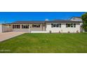 Well-maintained single-story home featuring a lush green lawn and a classic white exterior with black shutters at 4402 E Mitchell Dr, Phoenix, AZ 85018