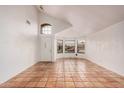 Living area with high ceilings, arched window, neutral paint, and red-tiled flooring at 7929 W Wescott Dr, Glendale, AZ 85308